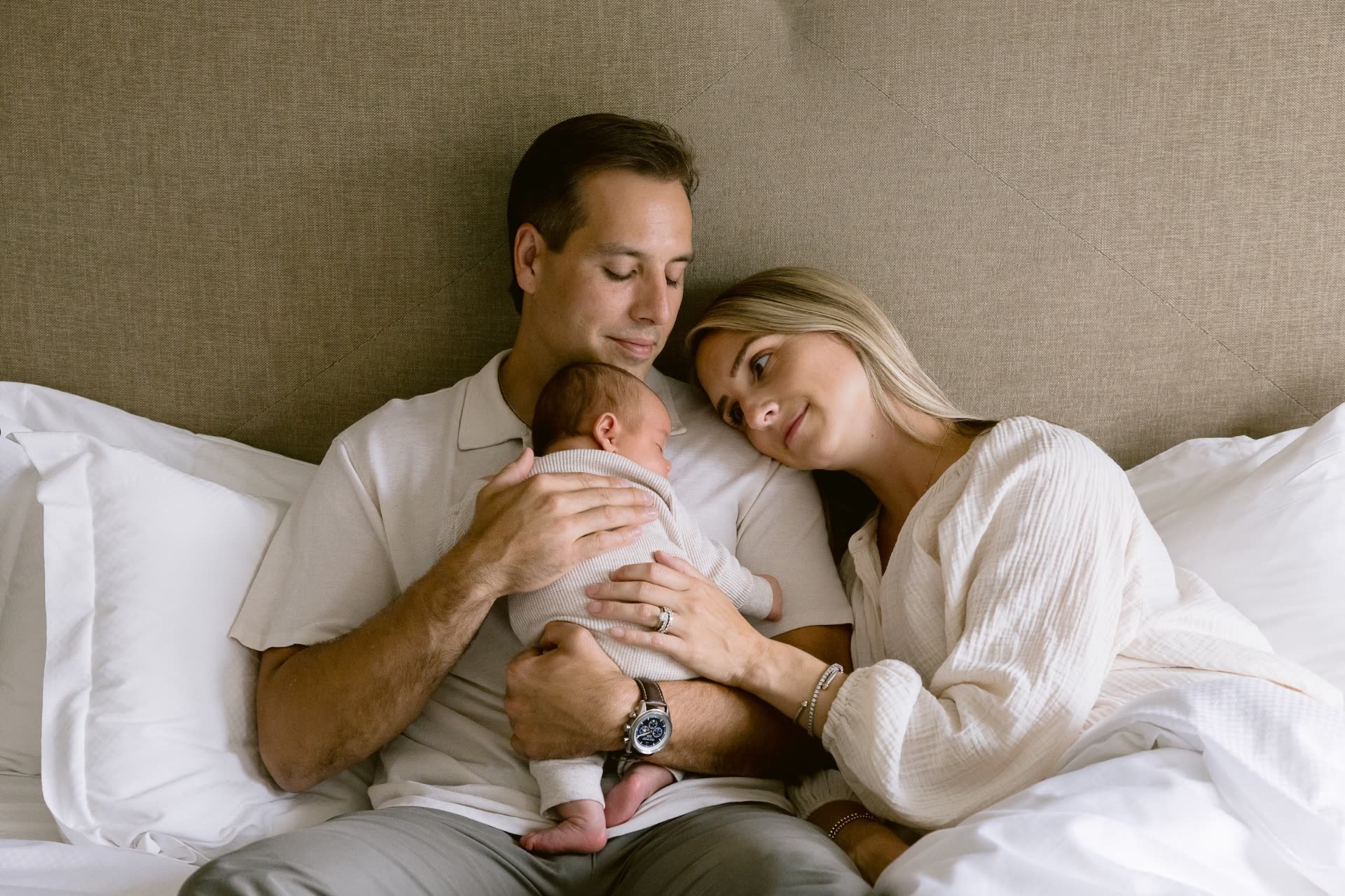 A mother and father resting in bed with their newborn during a Cassiana stay in Napa Valley